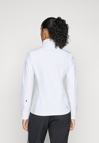 Weiße Sportjacke mit hohem Kragen, langen Ärmeln und tailliertem Design, das graue Akzente und einen subtilen Glanz aufweist. Keine sichtbaren Logos.