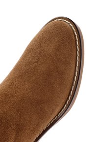 Stivale alla caviglia in suede marrone con punta arrotondata, cuciture a contrasto lungo la suola e una texture liscia.