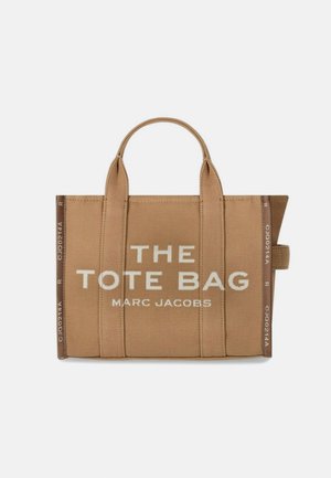 Beidzot kanvas soma ar dubultām augšējām rokturiem. Iezīmēta ar baltu tekstu "TOTE BAG" un "MARC JACOBS". Vienkāršs taisnstūra dizains.