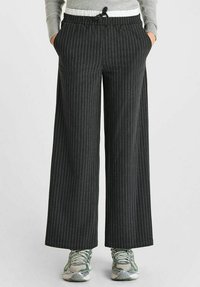 Pantalons noirs à rayures, à jambe large, avec une taille élastique et un cordon de serrage. Fabriqués en tissu léger, avec des poches latérales.