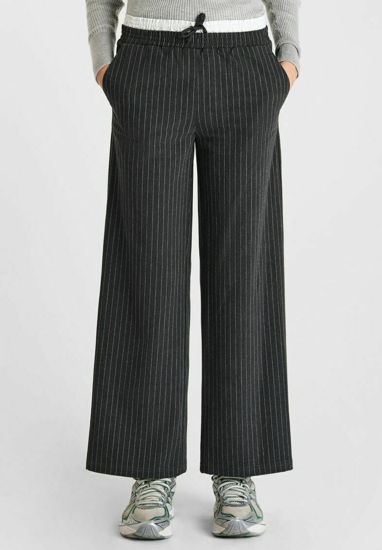 Pantalons noirs à rayures, à jambe large, avec une taille élastique et un cordon de serrage. Fabriqués en tissu léger, avec des poches latérales.