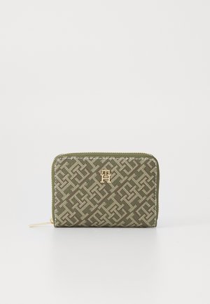 Green fabric wallet with a geometric pattern, gold hardware logo on the front, zip closure, and contrasting stitching.