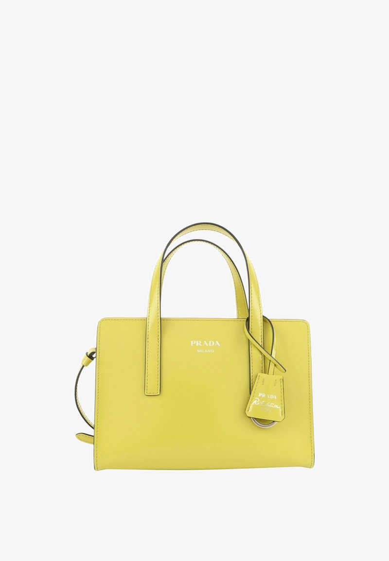 Sac à main en cuir jaune Prada Milano avec deux poignées et étiquette logo attachée sur fond blanc.
