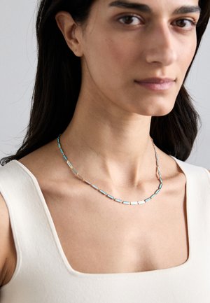 Hõbedatooni kaelakee, mis sisaldab vahelduvaid ristkülikukujulisi linke koos türkiissiniste aktsentidega, sile tekstuur ja lihtne, elegantne disain.