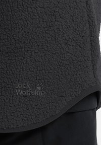 Schwarzer Fleece-Pullover mit strukturiertem Material, abgerundetem Saum und gesticktem "Jack Wolfskin"-Logo. Weiches, warmes Material.