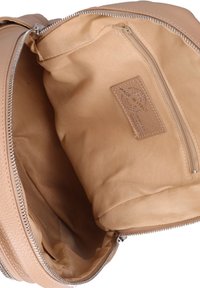 Interno di una borsa in pelle tan con rivestimento in tessuto liscio, tasca con zip e etichetta "Made in Italy". Contiene ampio spazio di archiviazione.