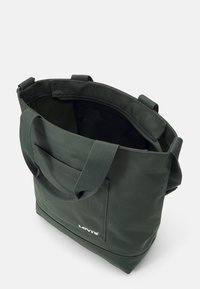 Zielona torba na ramię z płótna, z podwójnymi uchwytami, zewnętrzną kieszenią oraz logo Levi's. Wnętrze ma czarne wykończenie i przestronną komorę.