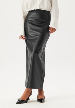 Black leather pencil skirt with a high waist, smooth texture, and body-hugging silhouette, paired with pointed black patent heels.