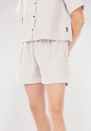 Light gray short-sleeve shirt with button closure and matching shorts. Fabric has a subtle texture and relaxed fit, with rolled hem at shorts.