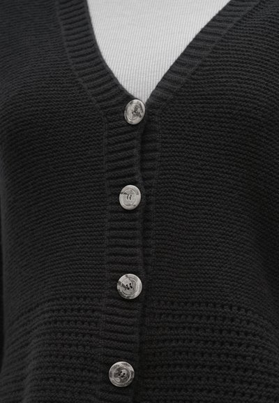 Fekete kötött kardigán V-nyakkivágással, öt ezüstszínű gombbal, bordázott részletekkel és texturált mintával a szöveten.