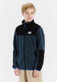 Fleece jack in marineblauw met zwarte accenten, volledige ritssluiting, hoge kraag, met een voorzijde logo patch en contrasterende blauwe rits.