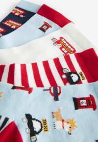 Mehrfarbige Socken mit verspielten Mustern: ein blauer Hintergrund, rote Akzente, weiße Streifen und Motive wie Taxis und Briefkästen.
