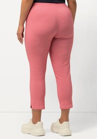 Červeno-bílé kárované capri kalhoty s pružným pasem a bočními štěrbinkami na lemech, kombinované se světle vybarvenými teniskami.