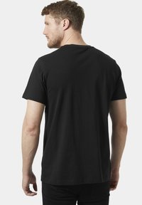 Camiseta de algodón negra con un cuello redondo estándar. Mangas cortas y un corte relajado. Textura suave y sin patrones o logotipos visibles.