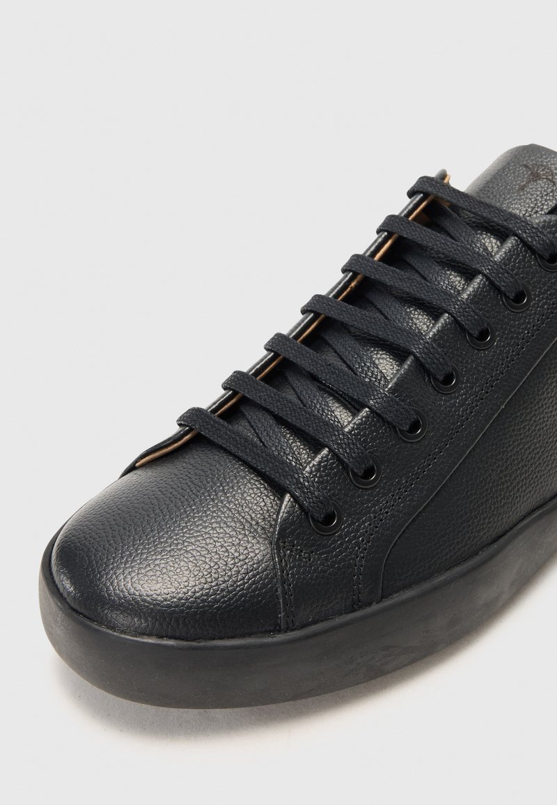 Czarne sneakersy z teksturowanej skórzanej cholewki, okrągłą gumową podeszwą, czarnymi sznurowadłami i mosiężnymi oczkami. Minimalistyczny design z gładkim wykończeniem.