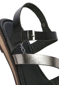 Sandal in pelle nera con cinturino in metallo argentato, dotato di chiusura con fibbia e soletta testurizzata. Il tacco è basso e la suola è liscia.