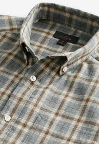 Cotton plaid shirt in gray, cream, and brown. Features a button-down collar and white buttons. Label shows brand "NEXT" and size "M."