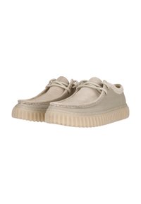 Zapatillas de lona beige con una superficie texturizada, punta redonda, costuras en contraste y una suela de goma translúcida. Presenta un diseño con cordones.