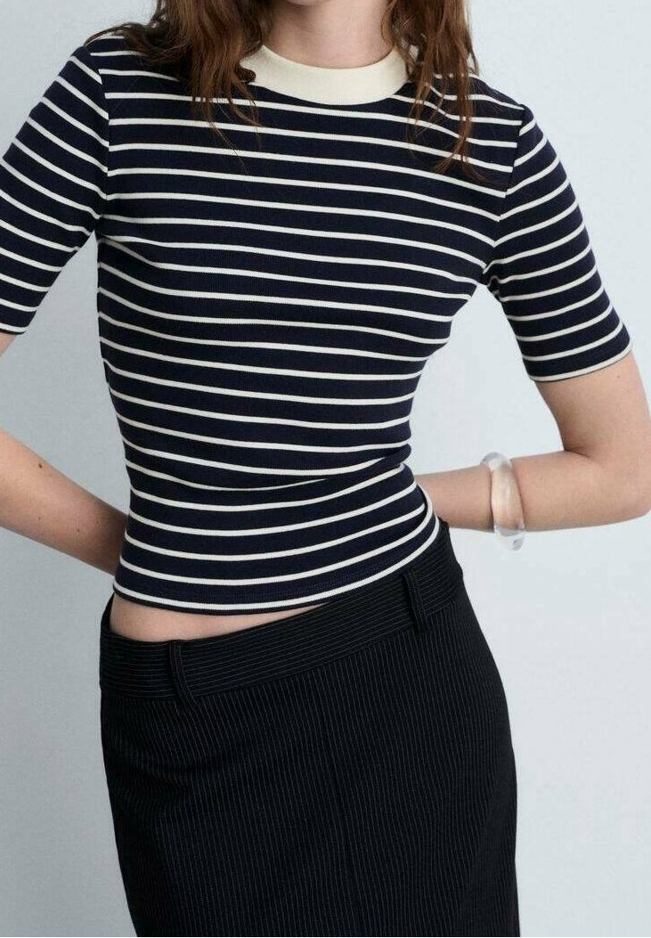 Námořnická a smetanová pruhovaná krátkosrstá blůza s přiléhavým střihem a kulatým výstřihem, zkombinovaná s černou sukní s jemným proužkem.