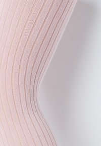 Jasnoróżowe, prążkowane rajstopy wykonane z miękkiego materiału, z pionowymi paskami, gładką fakturą oraz dopasowanym krojem.