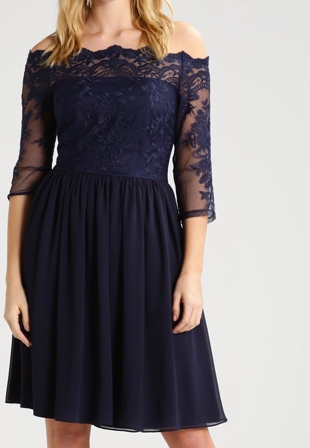 Robe bleu marine avec un design décolleté, corsage en dentelle, manches semi-transparentes 3/4 et jupe fluide. Détails de broderie florale tout au long.