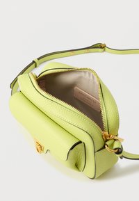 Grønn skinnveske med en teksturert overflate, gullglidelås og lys innside. Har en kort skulderstropp og en strukturert form.