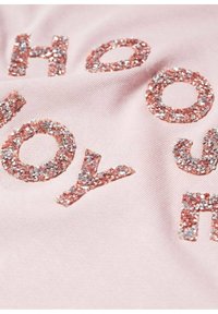 Tissu rose clair avec des lettres scintillantes en paillettes or rose et argent formant le mot "HOOPY". Surface texturée et brillante contrastant avec l'arrière-plan doux.