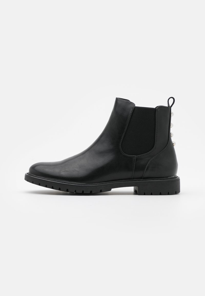 Bottine en cuir noir avec panneau latéral élastique, languette de tirage, semelle épaisse et clous décoratifs argentés à l'arrière.