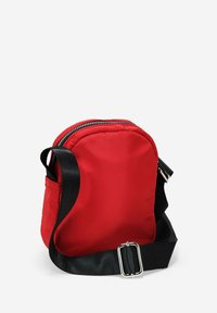 Bolso cruzado de nylon rojo con forma redondeada, cierre de cremallera plateado y correa ajustable negra. Textura suave, diseño minimalista.