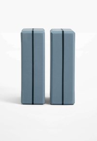 Deux blocs de yoga rectangulaires de couleur bleu clair, en mousse. Chaque bloc présente une bande noire courant verticalement le long d'un côté.
