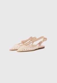 Nude slingback shoes with a pointed toe, made of mesh with silver studs, featuring a flat heel and a bow detail on the ankle strap.