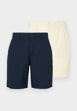 Due pettorine: una blu navy e una beige chiaro. Entrambe hanno una linea dritta, chiusura con bottone e un tessuto liscio e leggero.