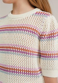 Stickad tröja med en lös, öppen väv i krämfärg. Har horisontella ränder i orange, rosa, lila och ljusblå. Korta ärmar och ribbad halsringning.