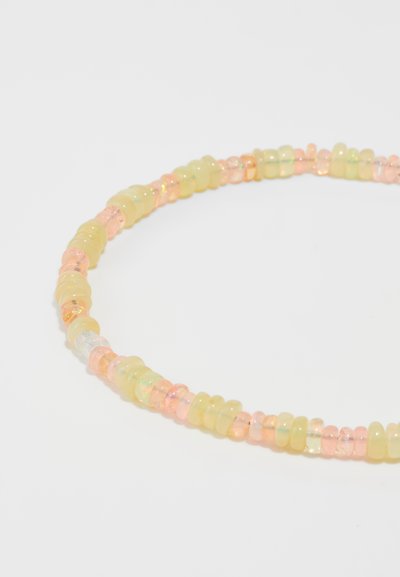Collar de cuentas de colores que presenta cuentas translúcidas en amarillo y rosa. Las cuentas son cilíndricas y tienen formas irregulares, con algunos detalles iridiscentes.