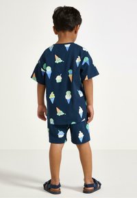 Mörkblå bomullsoutfit med kort ärm med ett upprepat mönster av glasskoner, inkluderar en löst sittande T-shirt och matchande shorts.