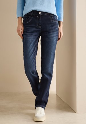 Dark blue denim jeans with a straight fit, featuring five-pocket design, contrast stitching, and a single button closure. White sneakers visible.