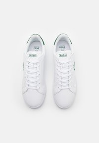 Vita sneakers i slät läder med gröna detaljer på häl och branding. Snörning med rund tå.