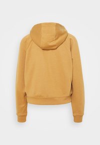 Hořčicově žlutá mikina s uvolněným střihem, která má kapuci se stahovací šňůrkou, žebrované manžety a zkrácený lem. Měkká textura bez viditelných log.