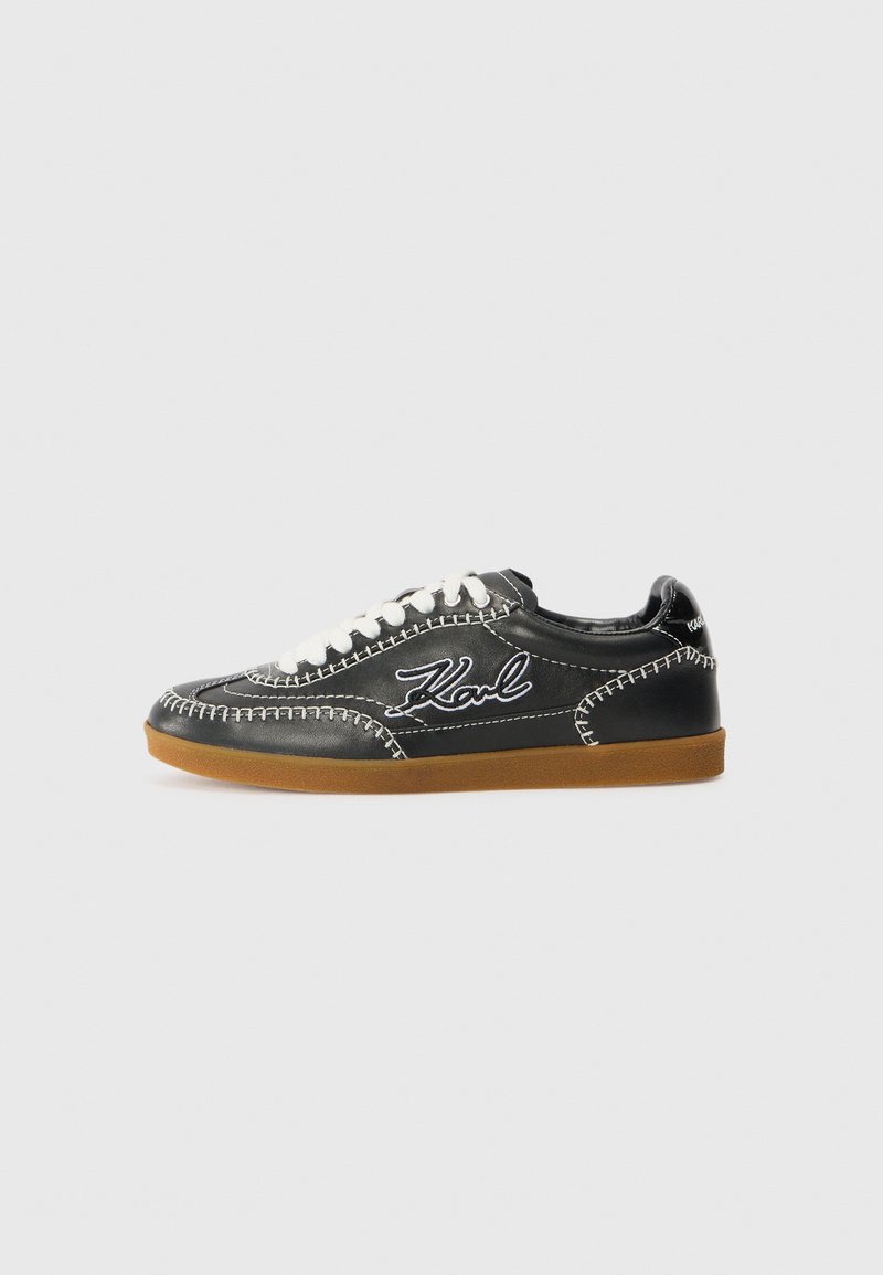 Black leather sneaker with white stitching and laces, featuring a rubber brown sole and embroidered "Karl" logo on the side.