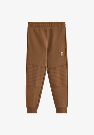 Brune børne joggebukser med elastisk linning, ribstrikkede manchetter, quiltede knælapper, sidelommer og "Play All Day" mærke på højre ben.