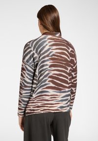 Strickpullover aus weichem Material mit einem farblich abgestimmten Zebra-Streifenmuster in Braun-, Blau- und Cremetönen; geripptem Ausschnitt und Saum.