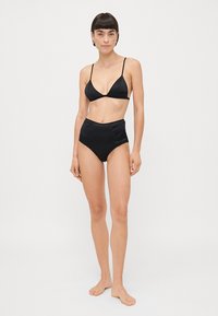 Melna bikini komplekts, kas ietver trijstūra braletu ar plānām siksniņām un augsto jostu apakšdaļu, izgatavots no gludas, spīdīgas auduma.