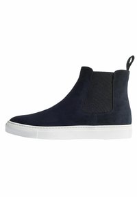 Marineblaue Wildleder-Ankelboots mit elastischen Seitenteilen und Zuglasche, ausgestattet mit einer weißen Gummisohle und minimalen Nähten.