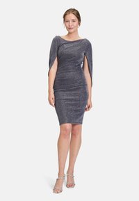 Robe navy scintillante avec une silhouette ajustée, design dénudé des épaules et manches drapées. Le tissu présente un léger éclat.