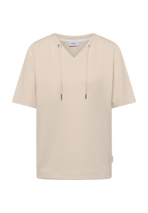 T-shirt beige côtelé à manches courtes avec col en V, cordons de serrage et œillets métalliques, étiqueté "Cecil" à l'intérieur du col.