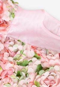 Blumenkleid mit einem pinken Mesh-Oberteil und gestuften Blumenauschnitt in verschiedenen Pink- und Grüntönen. Die Textur ist weich und geschichtet.