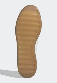 Adidas sko sula visas, med en strukturerad gummibotten i tan färg som har horisontella spår, vilket ger grepp och hållbarhet.