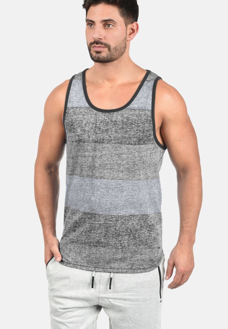 Grau und schwarz gestreifes Tanktop mit kontrastierendem dunklem Saum; weicher Stoff; ärmelloses Design; getragen mit hellgrauen Jogginghosen.