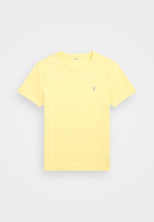 T-shirt gialla in cotone, con scollo rotondo, maniche corte e un piccolo logo blu sul lato sinistro del petto.
