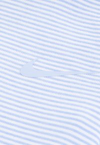 Svetlomodrá pruhovaná látka s mäkkou textúrou, ktorá má výrazné biele logo Nike Swoosh umiestnené výrazne na materiáli.